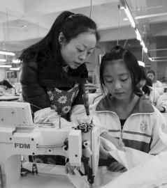 大英縣中等職業技術學校內，企業服裝技師正指導學生進行縫紉操作。